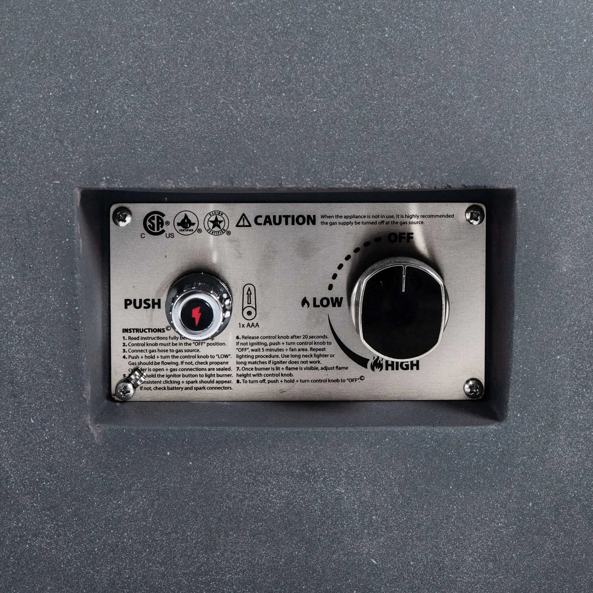 Close-up view of the Flame Havens Refuge Series 36-inch Round Natural Gas GFRC Concrete Fire Pit in Gray, highlighting the recessed stainless steel CSA-certified ignition control panel. The image clearly shows the push-button spark igniter, flame adjustment knob, OFF, LOW, and HIGH settings, and the brushed stainless control plate integrated into the textured gray GFRC concrete body for a clean, professional finish.