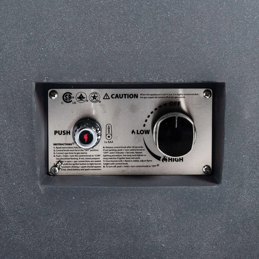 Close-up view of the Flame Havens Refuge Series 36-inch Round Natural Gas GFRC Concrete Fire Pit in Gray, highlighting the recessed stainless steel CSA-certified ignition control panel. The image clearly shows the push-button spark igniter, flame adjustment knob, OFF, LOW, and HIGH settings, and the brushed stainless control plate integrated into the textured gray GFRC concrete body for a clean, professional finish.
