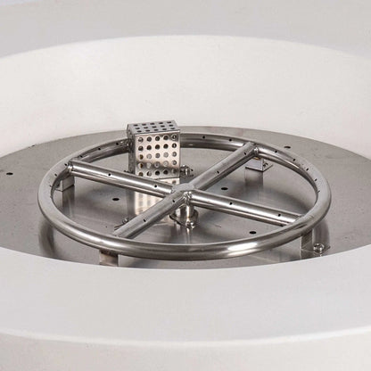 Close-up of the Flame Havens Refuge Series stainless steel burner and CSA-certified ignition assembly inside the 36-inch Round Natural Gas White GFRC Concrete Fire Pit. The precision-engineered circular burner, cross supports, and ignition housing demonstrate the premium construction designed for reliable outdoor fire performance.