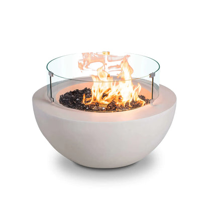 Front studio image of the Flame Havens Refuge Series 36-inch Round Natural Gas White GFRC Concrete Fire Pit operating with the optional tempered glass wind guard installed. Bright flames rise above premium black reflective tempered fire glass while the clear cylindrical wind guard with stainless steel mounting brackets enhances safety, flame stability, and the modern architectural appearance of this luxury outdoor fire pit.