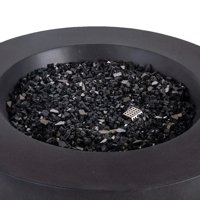 Close-up view of the Flame Havens Refuge Series 36-inch Round Propane Gas GFRC Concrete Fire Pit in Black, showcasing premium 1/2-inch Black Reflective Fire Glass evenly covering the stainless steel burner pan. The image highlights the smooth Graphite Black GFRC concrete finish, concealed CSA ignition, and luxurious media designed to create a modern outdoor centerpiece for patios and backyard living spaces.