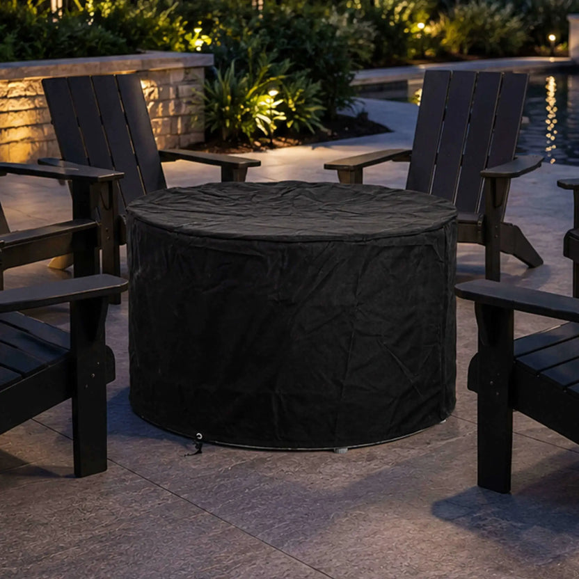 Lifestyle image of the Flame Havens Refuge Series 36-inch Round Propane Gas GFRC Concrete Fire Pit covered with the optional Black Canvas Fabric Cover and surrounded by Adirondack chairs on a luxury backyard patio beside a pool. The weatherproof cover protects the Graphite Black fire pit while maintaining a clean, finished appearance when not in use.