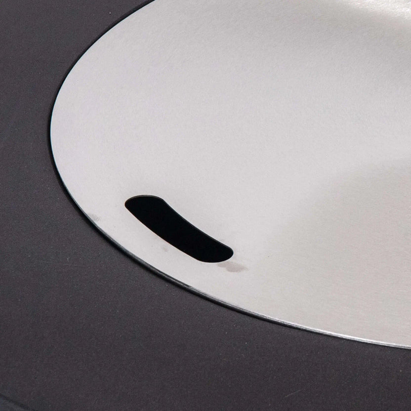 Close-up of the optional Stainless Steel Burner Cover installed on the Flame Havens Refuge Series 36-inch Round Propane Gas GFRC Concrete Fire Pit. The brushed stainless steel cover sits flush within the burner opening, transforming the fire pit into a functional tabletop while protecting the burner from weather and debris when not in use.