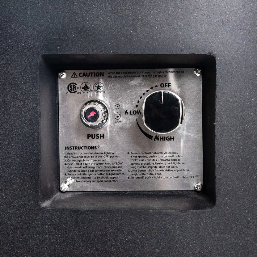 Close-up of the Flame Havens Refuge Series 36-inch Round Propane Gas GFRC Concrete Fire Pit recessed control panel featuring the CSA-certified push-button ignition and adjustable flame control valve. The stainless steel control plate is integrated into the Graphite Black GFRC concrete body, providing safe, reliable, and convenient propane fire pit operation.