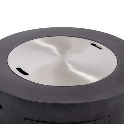 Flame Havens Refuge Series 36-inch Round Propane Gas GFRC Concrete Fire Pit in Graphite Black featuring the optional Stainless Steel Burner Cover installed flush within the burner opening. The brushed stainless steel cover transforms the fire pit into a functional tabletop while protecting the burner from weather, debris, and moisture when the fire feature is not in use.