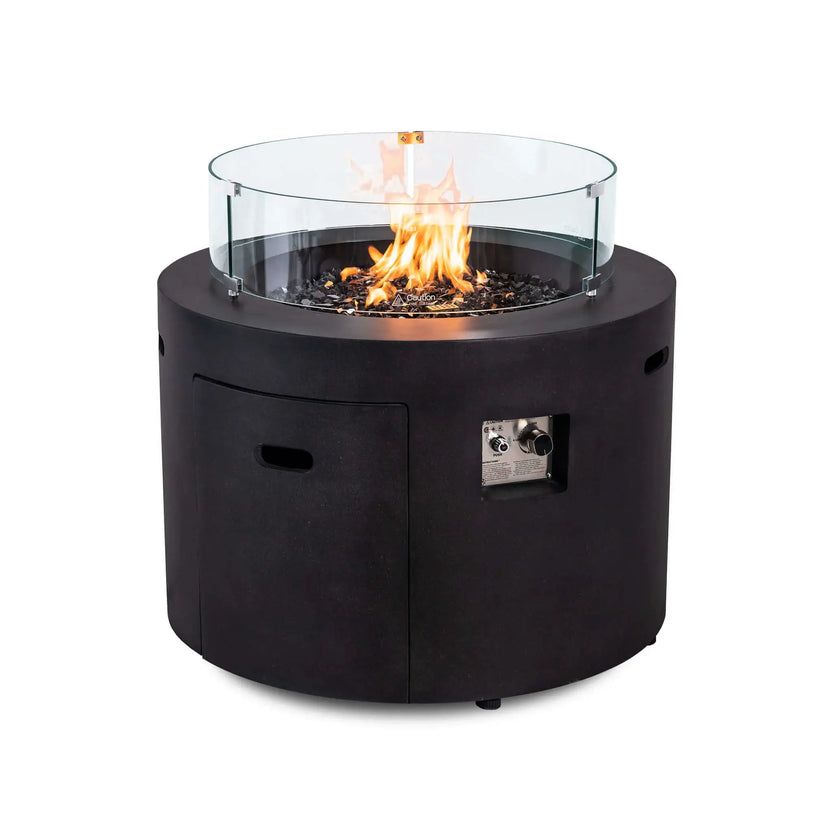 Flame Havens Refuge Series 36-inch Round Propane Gas GFRC Concrete Fire Pit featuring the optional tempered glass wind guard surrounding the natural propane flame. Premium Black Reflective Fire Glass, the Graphite Black GFRC concrete finish, and the clear glass wind guard combine to enhance flame protection while preserving an unobstructed view of the fire.