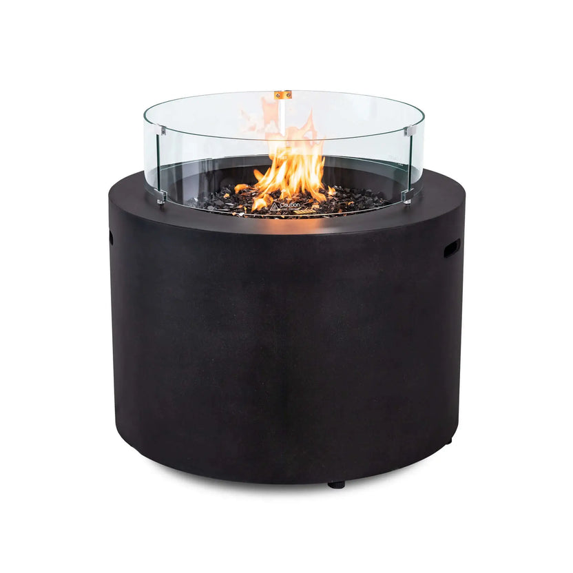 Flame Havens Refuge Series 36-inch Round Propane Gas GFRC Concrete Fire Pit featuring the optional tempered glass wind guard surrounding vibrant natural flames over premium Black Reflective Fire Glass. The Graphite Black GFRC concrete fire pit combines elegant modern styling with added flame protection, making it ideal for upscale patios, pool decks, and outdoor gathering spaces.