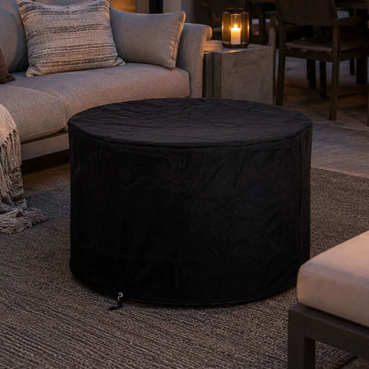 Lifestyle image of the Flame Havens Refuge Series 36-inch Round Propane Gas GFRC Concrete Fire Pit in Natural Gray protected with the fitted black canvas fabric cover. Positioned within a luxury outdoor seating area, the image demonstrates how the weather-resistant cover preserves the fire pit's appearance while complementing upscale patios and backyard entertainment spaces.
