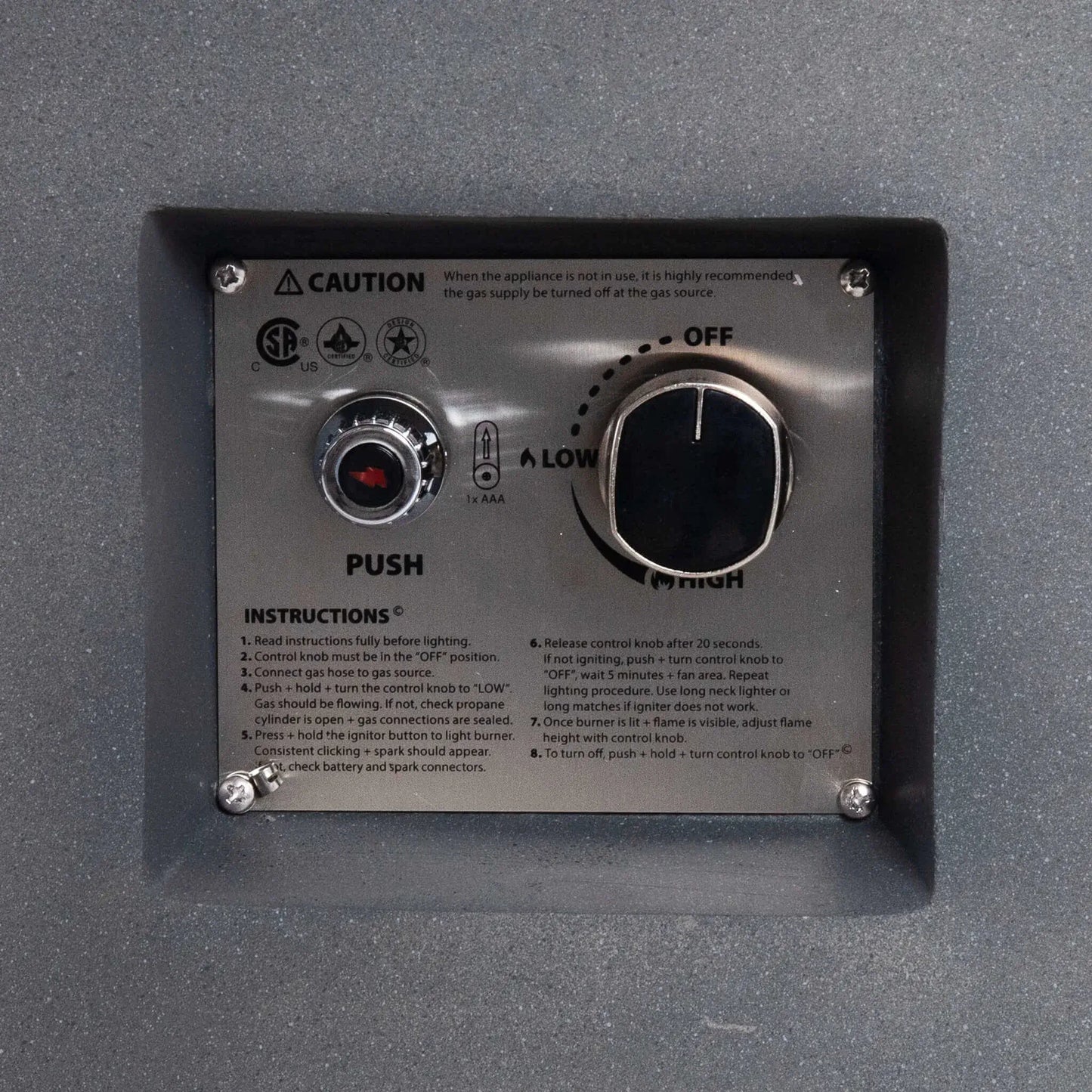 Close-up of the recessed control panel on the Flame Havens Refuge Series 36-inch Round Propane Gas GFRC Concrete Fire Pit. The image showcases the CSA-certified stainless steel ignition plate, push-button igniter, adjustable flame control knob, lighting instructions, and durable GFRC concrete surround for safe and reliable propane gas operation.