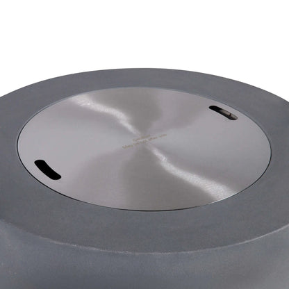 Top view of the Flame Havens Refuge Series 36-inch Round Propane Gas GFRC Concrete Fire Pit in Natural Gray with the optional stainless steel burner cover installed. The brushed stainless steel cover fits flush within the burner opening, converting the fire pit into a functional tabletop while protecting the burner assembly when not in use.