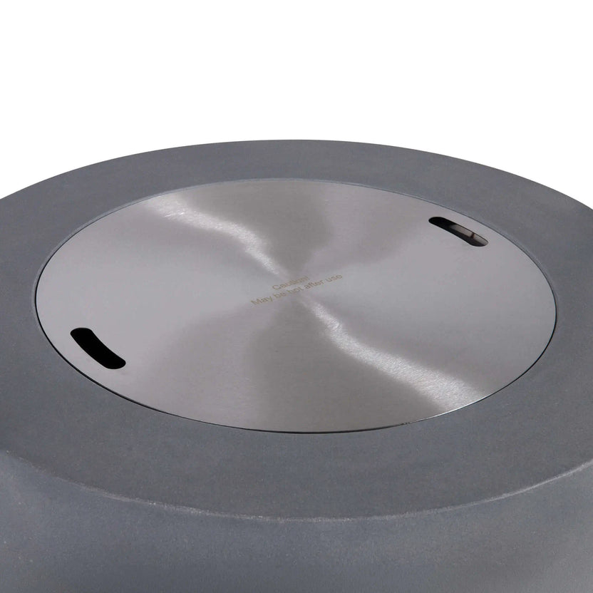 Top view of the Flame Havens Refuge Series 36-inch Round Propane Gas GFRC Concrete Fire Pit in Natural Gray with the optional stainless steel burner cover installed. The brushed stainless steel cover fits flush within the burner opening, converting the fire pit into a functional tabletop while protecting the burner assembly when not in use.