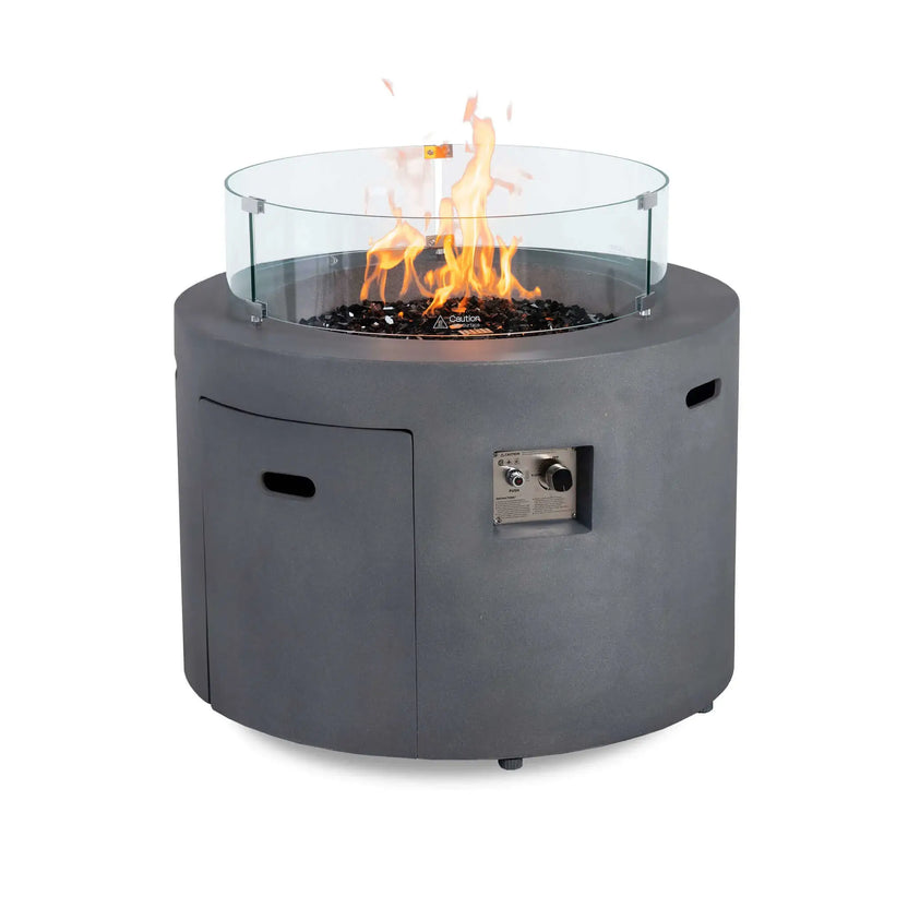 Rear view of the Flame Havens Refuge Series 36-inch Round Propane Gas GFRC Concrete Fire Pit in Natural Gray featuring tall flames, premium Black Reflective Fire Glass, and the optional tempered glass wind guard. The image demonstrates how the wind guard surrounds the burner while maintaining an unobstructed view of the flame and protecting it from outdoor breezes.