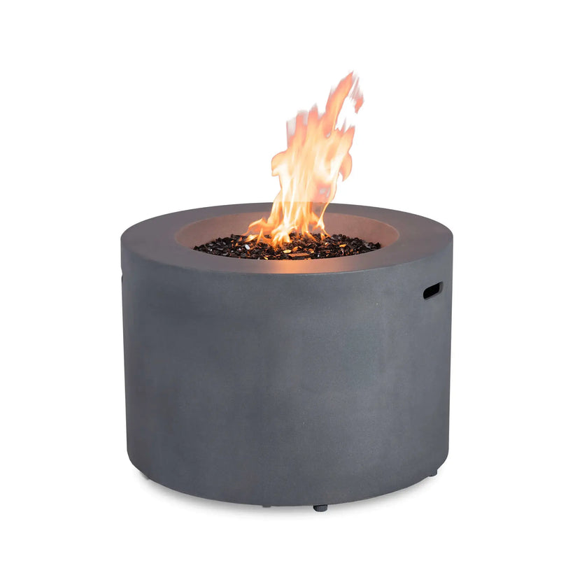 Rear view of the Flame Havens Refuge Series 36-inch Round Propane Gas GFRC Concrete Fire Pit in Natural Gray operating with tall propane flames above premium Black Reflective Fire Glass. This angle emphasizes the clean cylindrical GFRC concrete design without the control panel visible, showcasing the elegant appearance from every viewing angle.
