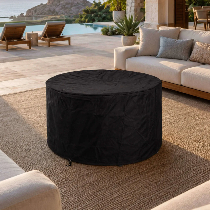 Lifestyle image of the Flame Havens Refuge Series 36-inch Round Propane Gas GFRC Concrete Fire Pit in Ivory White protected with the optional black canvas fabric cover. Positioned on a luxury outdoor patio beside a modern pool and comfortable seating, the weather-resistant cover helps protect the fire pit when not in use while blending seamlessly into upscale outdoor living spaces.