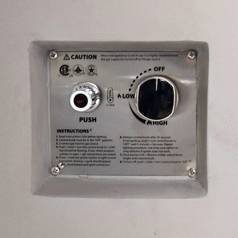 Close-up of the CSA-certified ignition control panel on the Flame Havens Refuge Series 36-inch Round Propane Gas GFRC Concrete Fire Pit in Ivory White. The recessed stainless steel panel features the push-button igniter, flame adjustment control knob, OFF-LOW-HIGH settings, lighting instructions, and safety certifications for reliable propane gas operation.