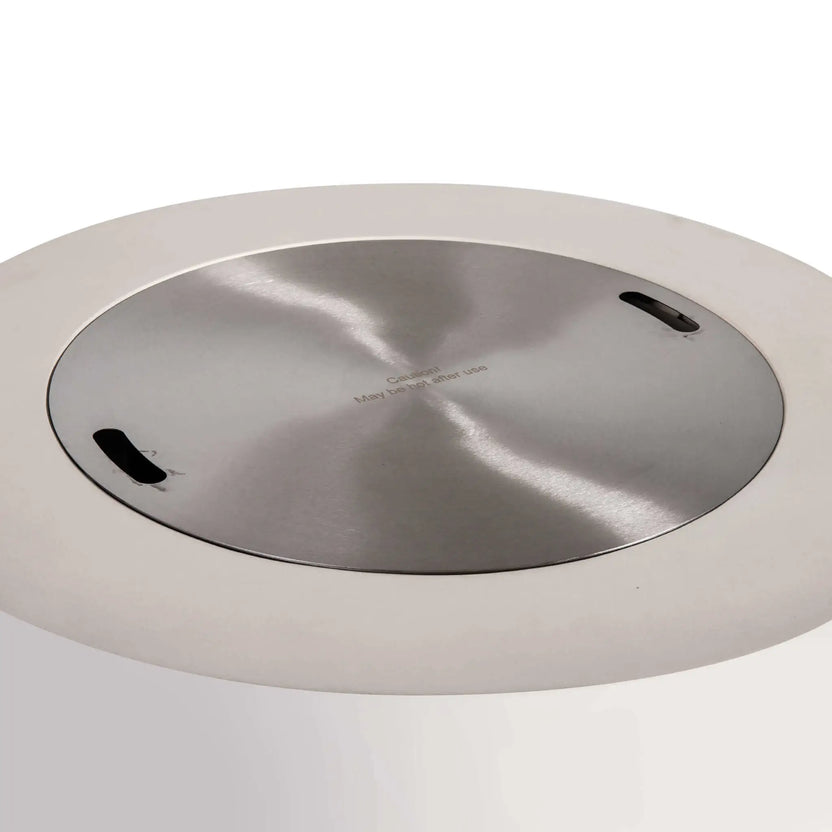 Top view of the Flame Havens Refuge Series 36-inch Round Propane Gas GFRC Concrete Fire Pit in Ivory White with the optional Stainless Steel Burner Cover installed. The brushed stainless steel cover fits flush inside the burner opening, creating a smooth tabletop surface while protecting the burner when the fire pit is not in operation.