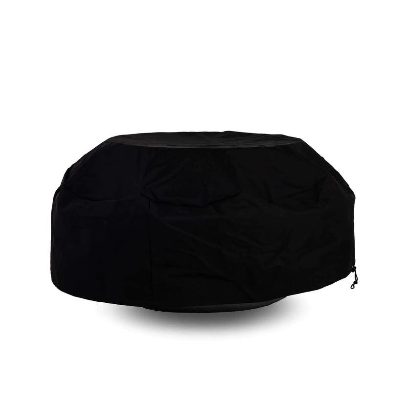 Side view of the Flame Havens Refuge Series 43-inch Round Natural Gas Black GFRC Concrete Fire Pit fitted with a black canvas fabric cover while a tempered glass wind guard remains installed underneath. The protective cover accommodates the wind guard, offering convenient weather protection without requiring accessory removal.