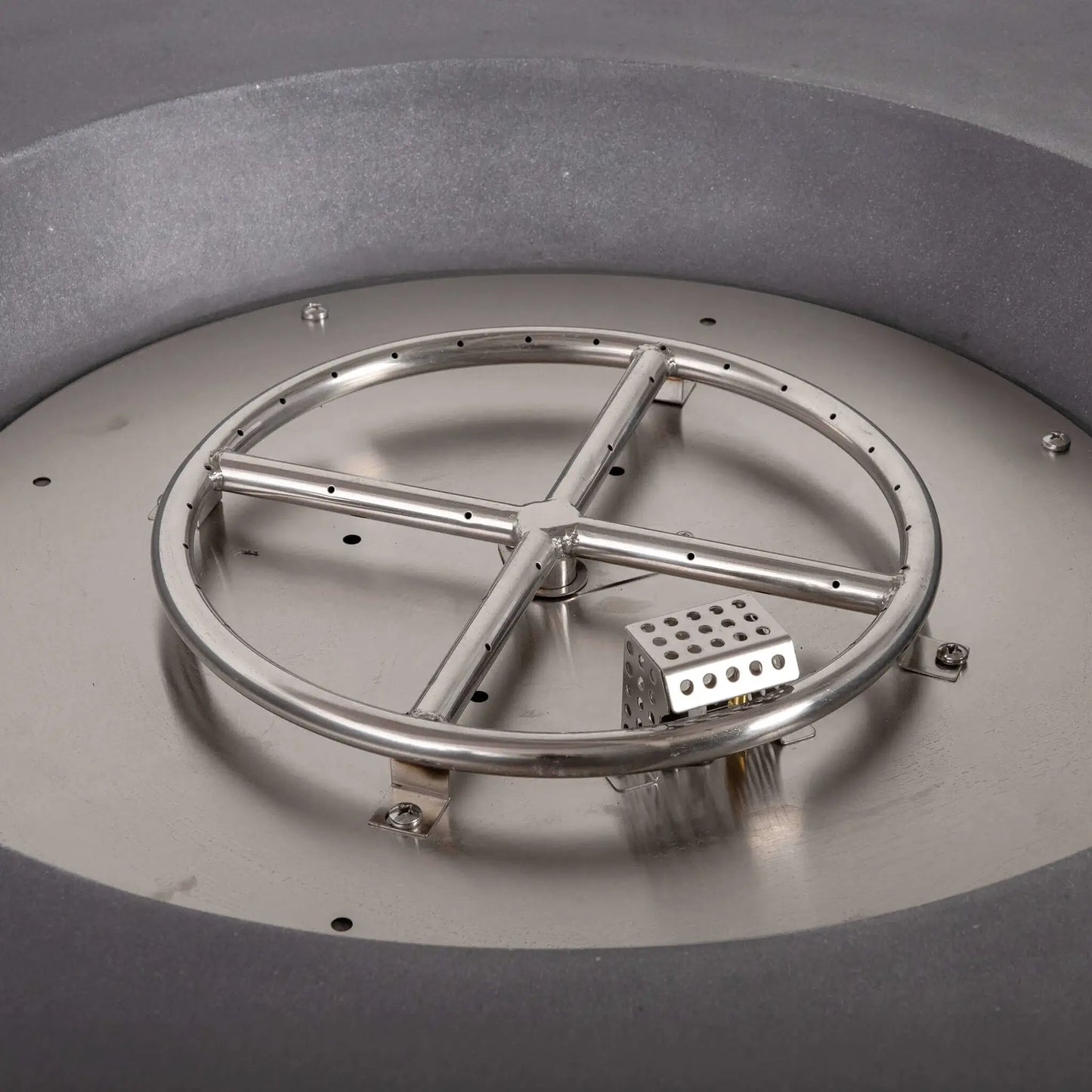 Detailed view of the stainless steel burner assembly and CSA-certified ignition system inside the Flame Havens Refuge Series 43-inch Round Natural Gas Gray GFRC Concrete Fire Pit. The circular burner ring, ignition module, and stainless steel burner pan are displayed before fire glass installation, highlighting the fire pit's premium engineering and durable construction.