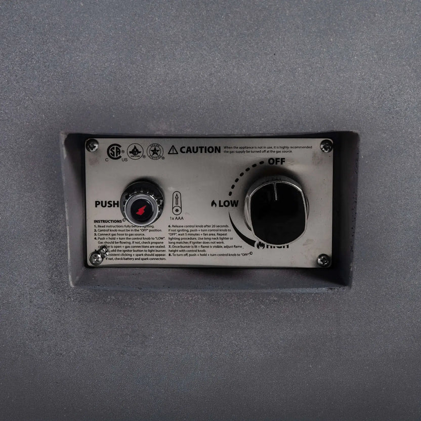 Close-up of the Flame Havens Refuge Series 43-inch Round Natural Gas Fire Pit control panel featuring the CSA-certified ignition system, push-button spark igniter, flame adjustment knob, and engraved operating instructions. The recessed stainless steel control assembly provides convenient access while maintaining a clean exterior appearance.