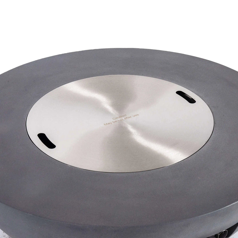 Top view of the Flame Havens Refuge Series 43-inch Round Natural Gas Gray GFRC Concrete Fire Pit with the precision-fit stainless steel burner cover installed. The brushed stainless cover sits flush within the recessed burner opening, transforming the fire pit into a functional tabletop while protecting the burner when not in use.
