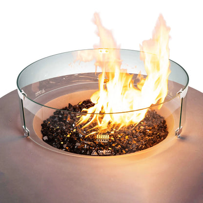 Close-up of the Flame Havens Refuge Series 43-inch Round Natural Gas Gray GFRC Concrete Fire Pit featuring reflective tempered black fire glass, a clear tempered glass wind guard, and a bright natural gas flame. The circular wind guard protects the flame while maintaining an open view of the fire for safe outdoor enjoyment.