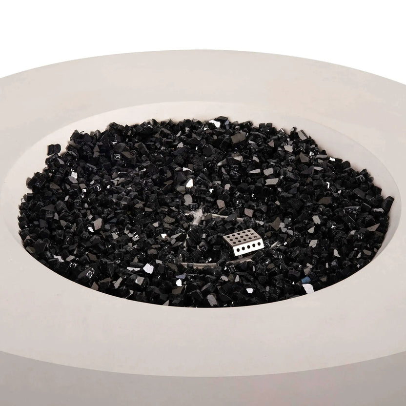 Top view of the Flame Havens Refuge Series 43-inch Round Natural Gas White GFRC Concrete Fire Pit filled with reflective black fire glass. The premium fire media surrounds the stainless steel burner and ignition assembly, creating a clean, contemporary appearance before the natural gas fire is ignited.