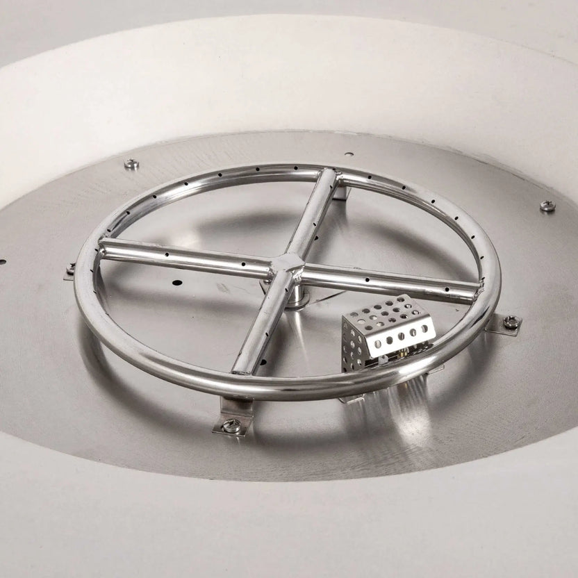 Close-up of the Flame Havens Refuge Series 43-inch Round Natural Gas White GFRC Concrete Fire Pit showing the stainless steel burner ring, CSA-certified ignition system, and ignition hood installed inside the stainless burner pan. This detailed view highlights the premium internal components before black fire glass is added.