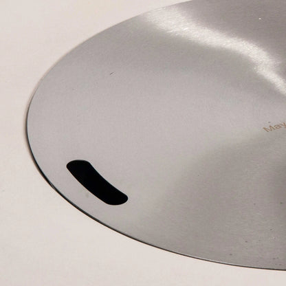Detailed close-up of the stainless steel burner cover designed for the Flame Havens Refuge Series 43-inch Round Natural Gas White GFRC Concrete Fire Pit. The brushed stainless cover sits flush within the burner opening and features integrated hand slots for easy removal while protecting the burner when the fire pit is not in use.