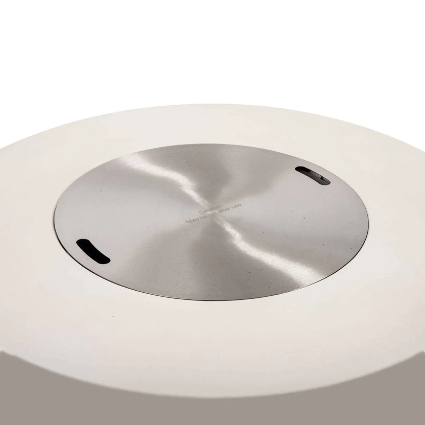 Front studio image of the Flame Havens Refuge Series 43-inch Round Natural Gas White GFRC Concrete Fire Pit with the stainless steel burner cover installed. The flush-mounted brushed stainless cover transforms the fire pit into a clean tabletop surface while concealing the burner beneath.