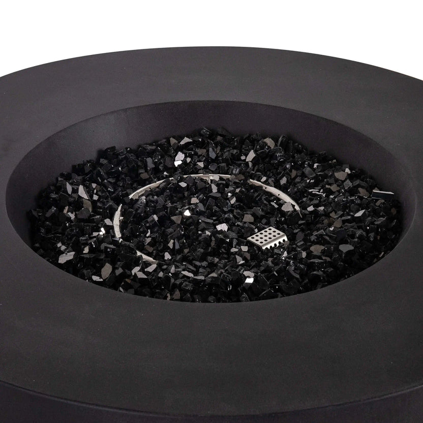 Close-up view of the Flame Havens Refuge Series 43-inch Round Propane Gas GFRC Concrete Fire Pit in Black, showcasing the premium black concrete finish, circular stainless steel burner, CSA ignition system, and 1/2-inch black reflective fire glass evenly surrounding the burner. The image highlights the clean recessed burner pan, modern round design, and high-end craftsmanship of this luxury outdoor propane fire pit.