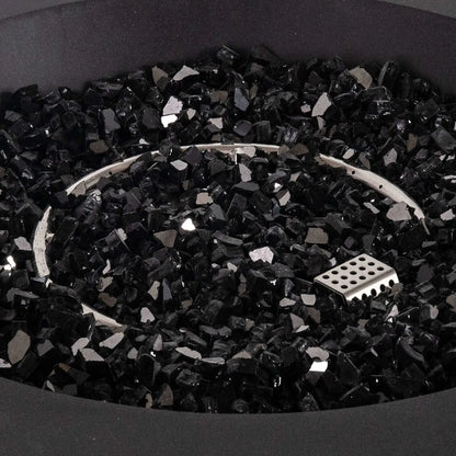Detailed close-up of the Flame Havens Refuge Series 43-inch Round Propane Gas GFRC Concrete Fire Pit featuring premium 1/2-inch black reflective fire glass surrounding the stainless steel circular burner and CSA ignition system. The image emphasizes the luxurious reflective media, precision burner layout, and smooth black concrete finish.