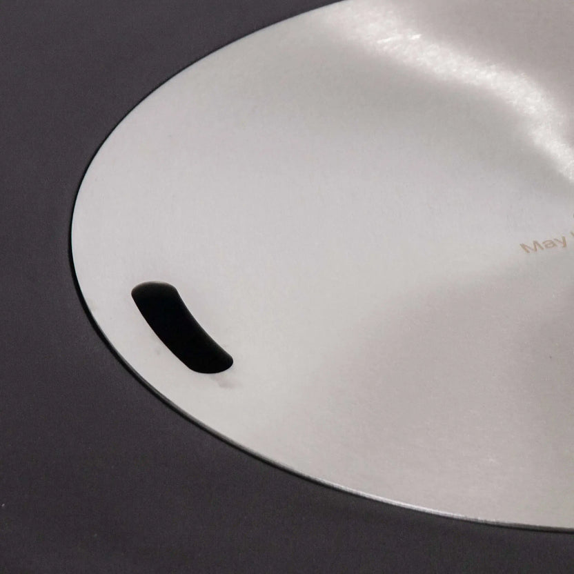 Close-up of the optional stainless steel burner cover installed on the Flame Havens Refuge Series 43-inch Round Propane Gas GFRC Concrete Fire Pit. The brushed stainless cover sits flush within the recessed burner opening, transforming the fire feature into a clean tabletop surface while protecting the burner when not in use.