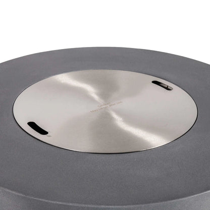 The Flame Havens Refuge Series 43-inch Round Propane Gas GFRC Concrete Fire Pit in Gray featuring the optional stainless steel burner cover installed flush within the burner opening. The brushed stainless steel cover creates a clean tabletop surface while protecting the burner system when the fire pit is not in use, complementing the modern GFRC concrete design.