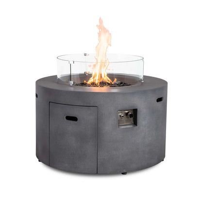 The Flame Havens Refuge Series 43-inch Round Propane Gas GFRC Concrete Fire Pit in Gray operating with premium black reflective fire glass and the optional tempered glass wind guard installed. The transparent wind guard surrounds the flame while providing protection from wind and preserving clear views of the fire from every angle.