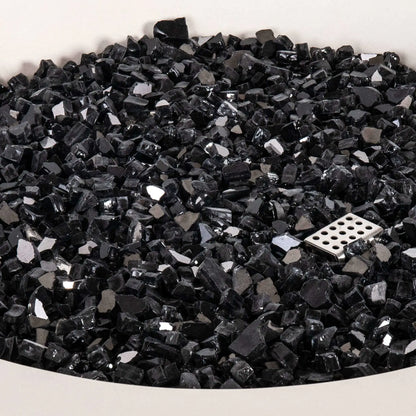 Detailed close-up of the tempered black reflective fire glass inside the Flame Havens Refuge Series 43-inch Round Propane Gas GFRC Concrete Fire Pit in White. The image highlights the premium reflective glass media surrounding the stainless steel CSA ignition component, showcasing the quality, depth, and polished finish of the fire feature.