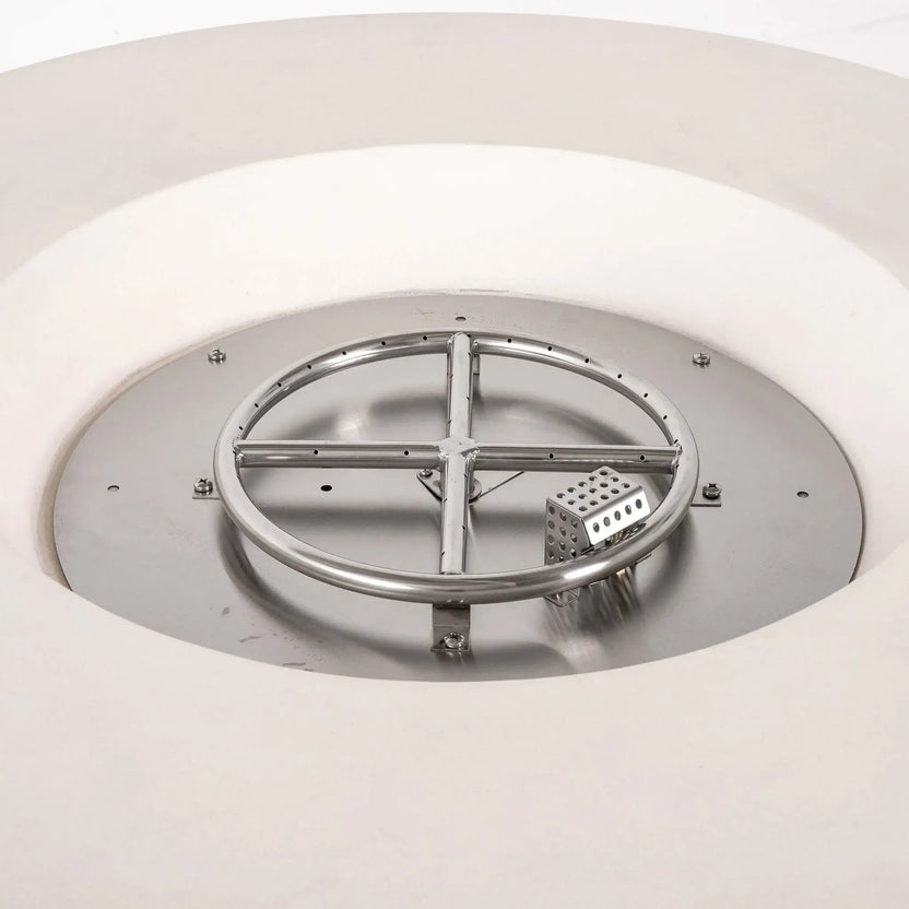 Close-up of the stainless steel burner assembly and CSA-certified ignition system inside the Flame Havens Refuge Series 43-inch Round Propane Gas GFRC Concrete Fire Pit in White. The image showcases the precision burner ring, ignition housing, and stainless burner pan designed for reliable performance and even flame distribution.