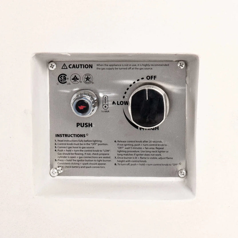 Close-up of the recessed CSA-certified ignition and flame control panel on the Flame Havens Refuge Series 43-inch Round Propane Gas GFRC Concrete Fire Pit in White. The image highlights the push-button spark igniter, adjustable flame control knob, stainless steel control plate, lighting instructions, and integrated safety labeling.