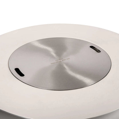 The Flame Havens Refuge Series 43-inch Round Propane Gas GFRC Concrete Fire Pit in White fitted with the optional brushed stainless steel burner cover. The cover sits flush within the burner opening, transforming the fire pit into a stylish outdoor table while preserving the clean lines and premium GFRC concrete construction.