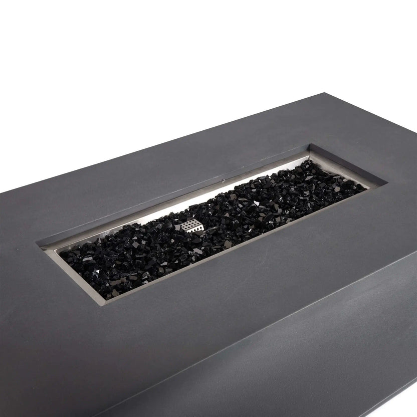 Angled top view of the Flame Havens Refuge Series 56 x 30 x 15 inch rectangle natural gas GFRC concrete fire pit in gray, showcasing the stainless steel burner pan filled with reflective tempered black fire glass. The image highlights the clean rectangular burner opening and modern architectural design.