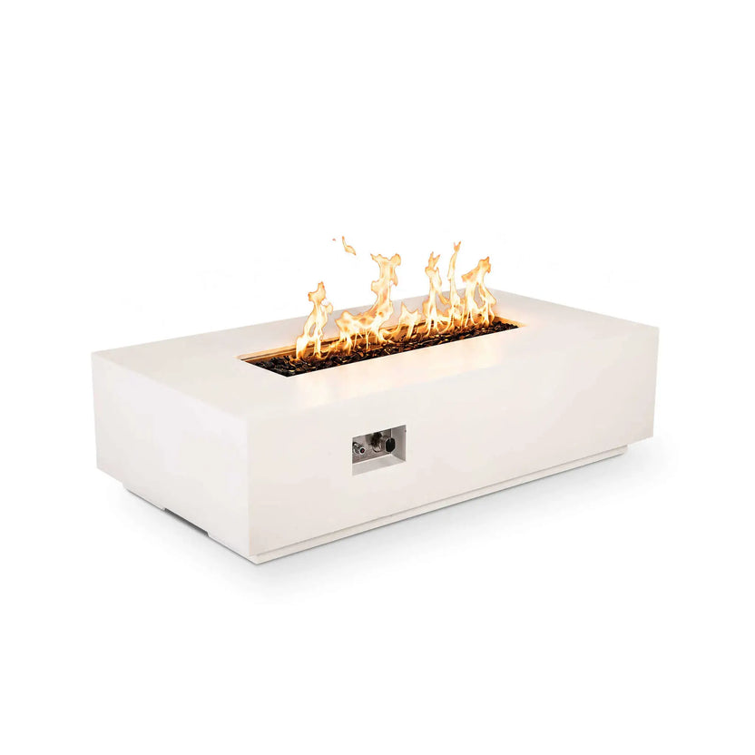 Angled view of the Flame Havens Refuge Series 56 x 30 x 15 inch rectangle natural gas white GFRC fire pit featuring active flames over reflective tempered black fire glass with the recessed stainless steel control panel visible on the front. The image showcases both elegant styling and convenient integrated ignition controls.