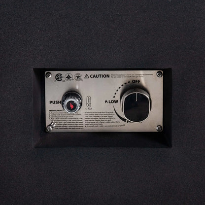 Detailed close-up of the Flame Havens Refuge Series 56 x 30 x 15 inch rectangle natural gas fire pit control panel, highlighting the CSA-certified ignition system, push-button spark igniter, adjustable gas control knob, and stainless steel mounting plate recessed into the black GFRC body.