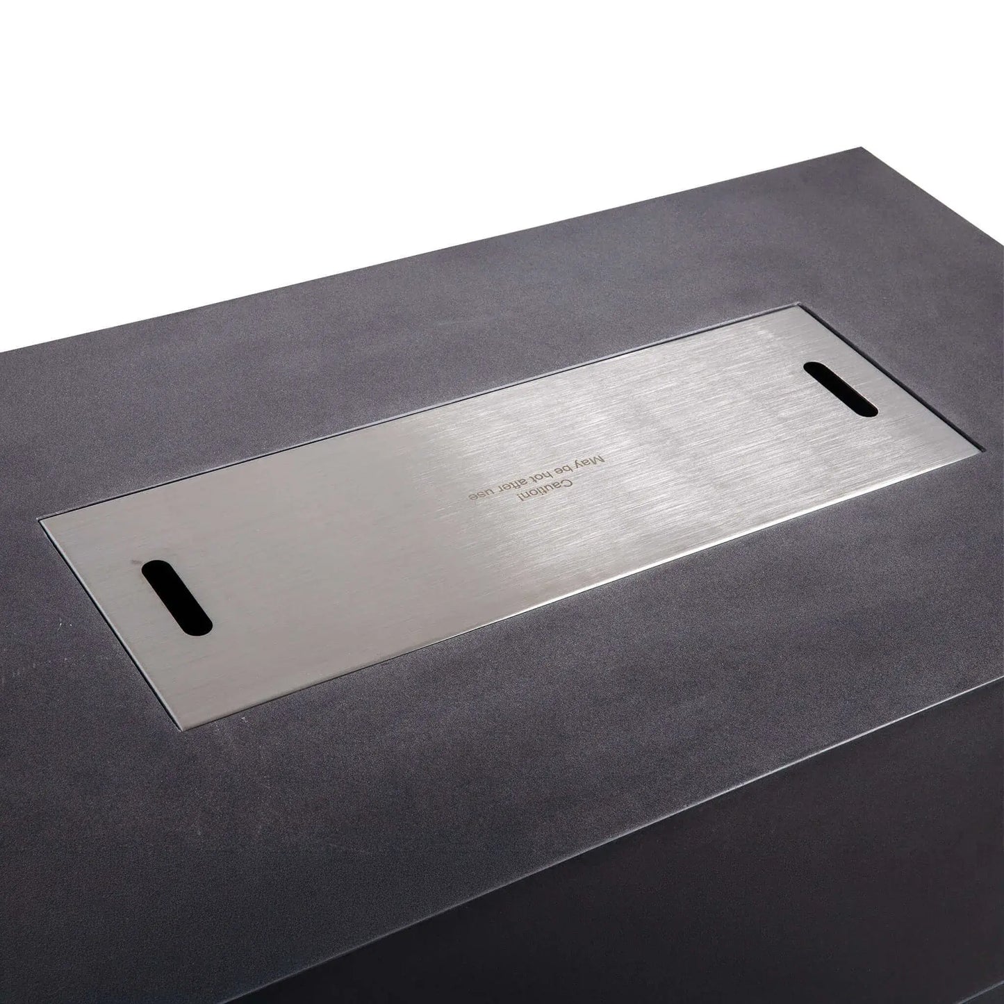 Close-up of the Flame Havens Refuge Series 56 x 30 x 15 inch rectangle natural gas GFRC concrete fire pit featuring the flush-mounted brushed stainless steel burner cover with integrated lifting slots, creating a sleek tabletop surface against the black concrete finish.
