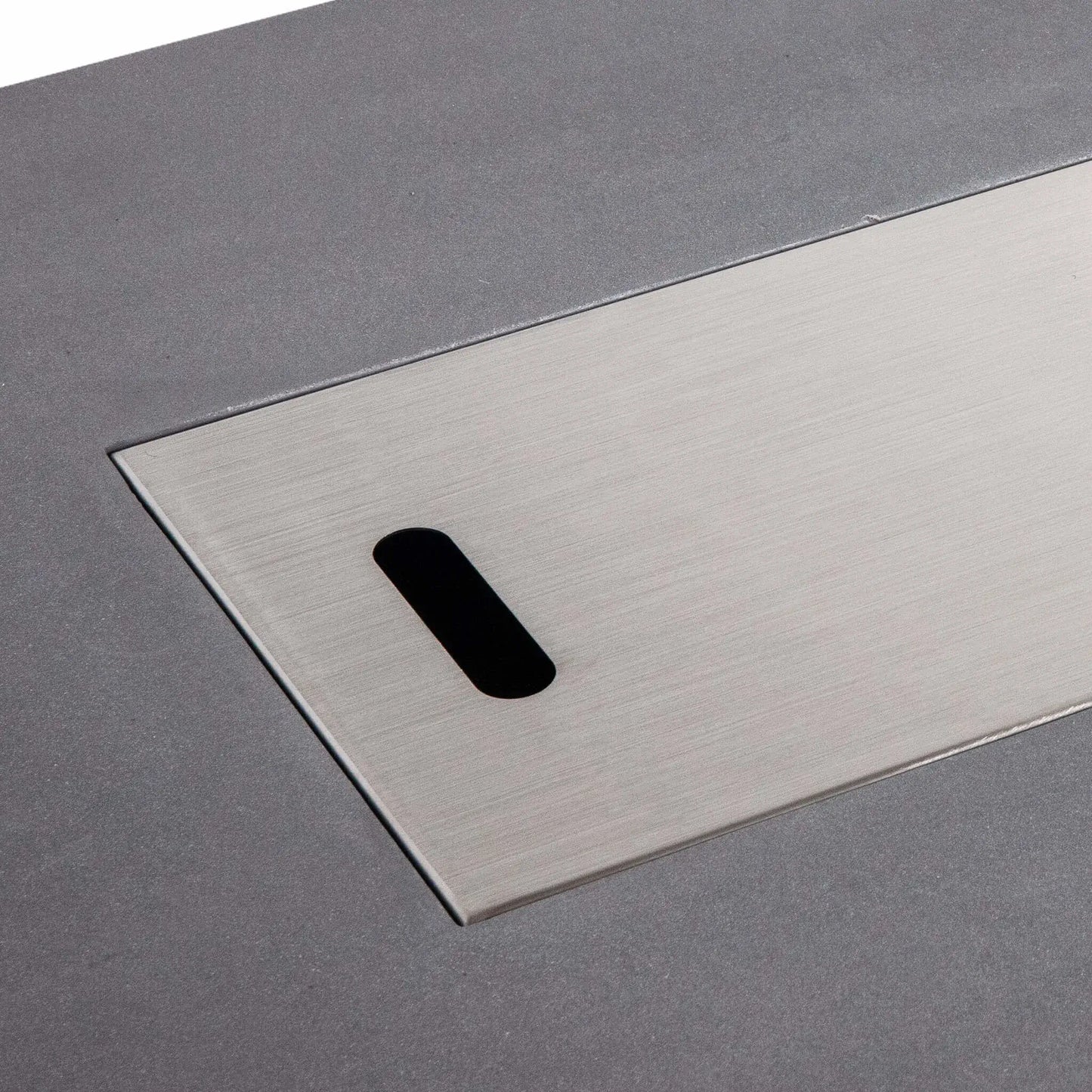 Close-up of the Flame Havens Refuge Series 56 x 30 x 15 inch rectangle natural gas gray GFRC fire pit with the brushed stainless steel burner cover installed. The precision-fit cover sits flush within the burner opening, providing a clean tabletop appearance when the fire feature is not in use.