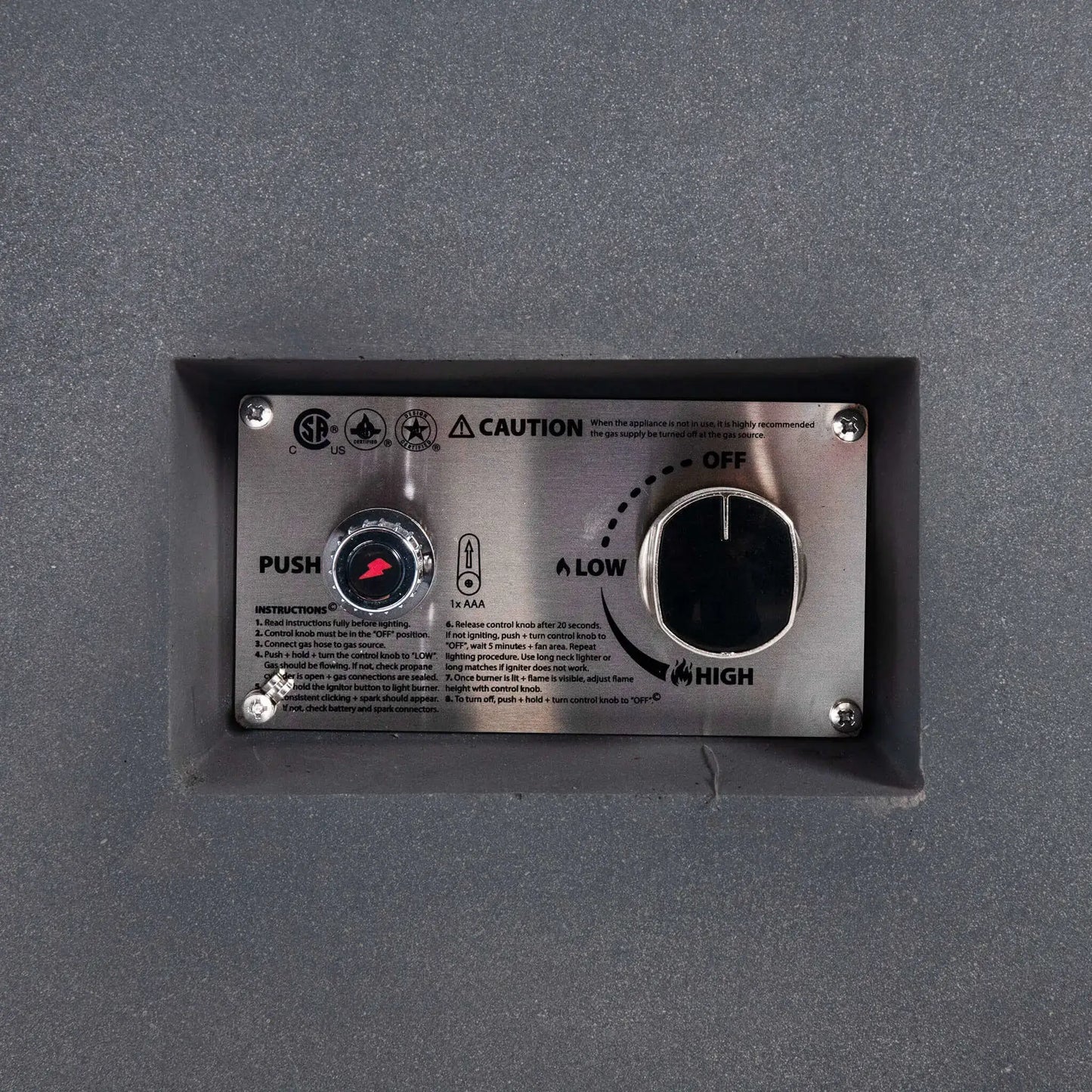 Close-up of the Flame Havens Refuge Series 56 x 30 x 15 inch rectangle natural gas gray GFRC fire pit recessed control panel, featuring the CSA-certified ignition button, flame adjustment knob, lighting instructions, and stainless steel faceplate for reliable and convenient operation.