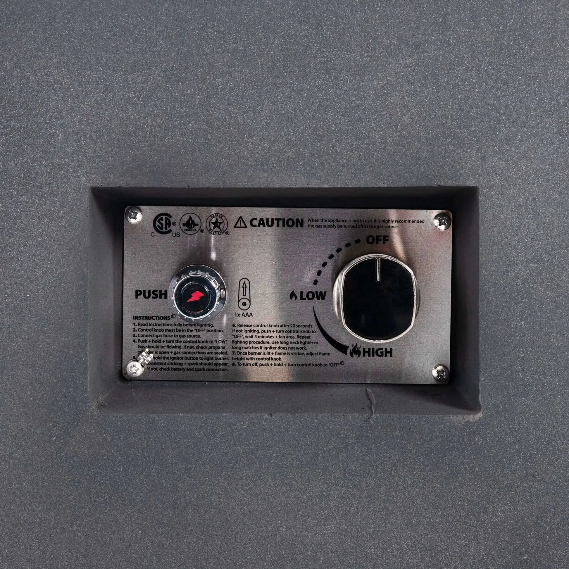 Close-up of the Flame Havens Refuge Series 56 x 30 x 15 inch rectangle natural gas gray GFRC fire pit recessed control panel, featuring the CSA-certified ignition button, flame adjustment knob, lighting instructions, and stainless steel faceplate for reliable and convenient operation.