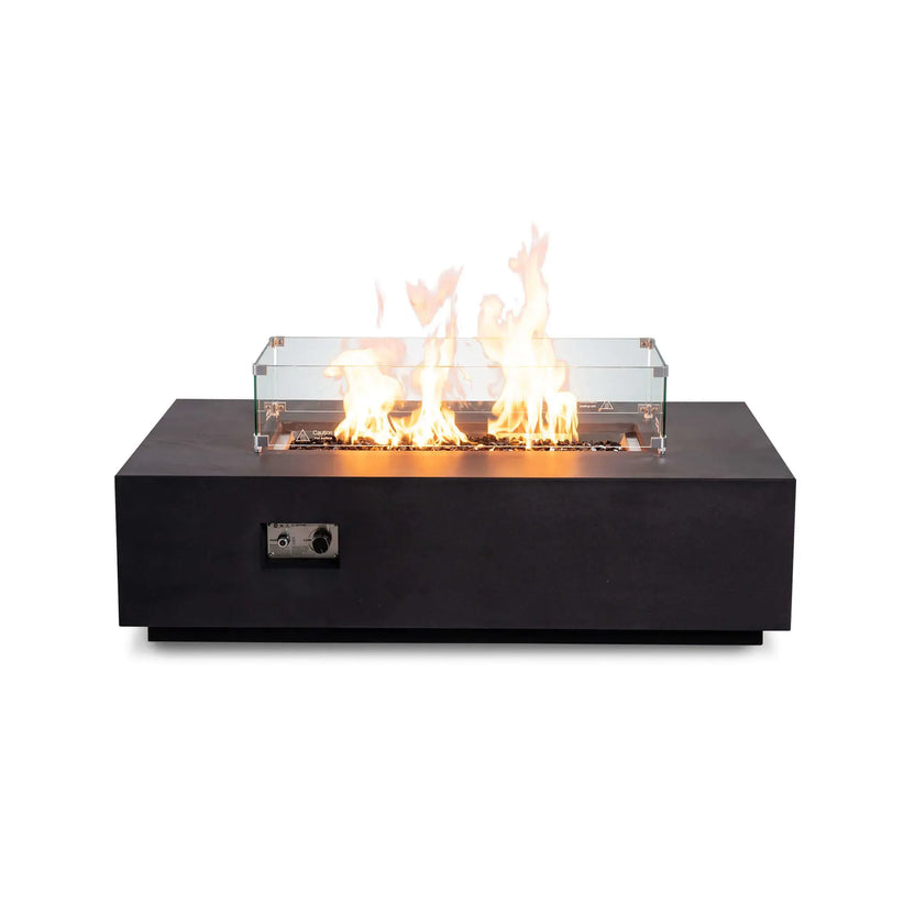 Straight front view of the Flame Havens Refuge Series 56 x 30 x 15 inch rectangle natural gas black GFRC fire pit with reflective tempered black fire glass, active flames, and a premium tempered glass wind guard installed. The concealed controls create a clean, modern architectural appearance.