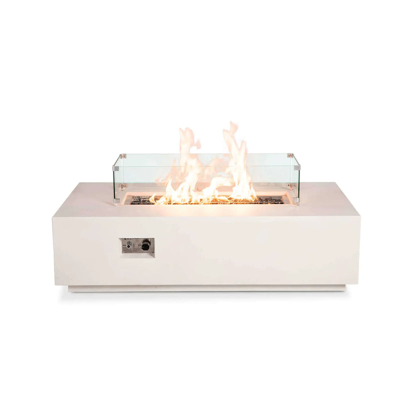 Front view of the Flame Havens Refuge Series 56 x 30 x 15 inch rectangle natural gas white GFRC concrete fire pit featuring the tempered glass wind guard and reflective tempered black fire glass. Tall flames burn evenly inside the clear wind guard, highlighting the modern rectangular design while maintaining unobstructed views from every angle.