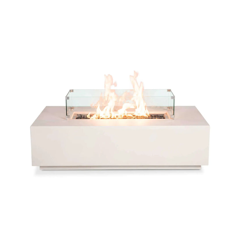 Front product image of the Flame Havens Refuge Series 56 x 30 x 15 inch rectangle natural gas white GFRC concrete fire pit equipped with a tempered glass wind guard and reflective tempered black fire glass. The stainless steel burner produces tall, even flames while the clear wind guard enhances safety without obstructing the contemporary linear fire display.