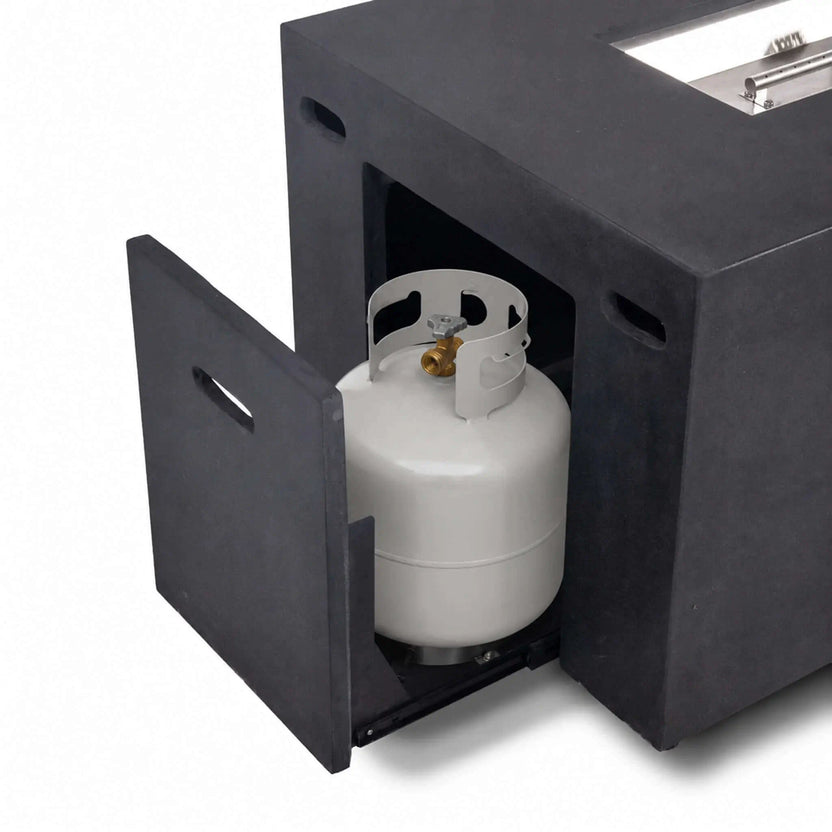 Open hidden propane tank drawer with a standard propane cylinder inside the black Flame Havens Refuge Series 56 x 30 x 24-inch rectangular GFRC concrete fire pit, demonstrating the concealed slide-out tank storage and easy-access door design.