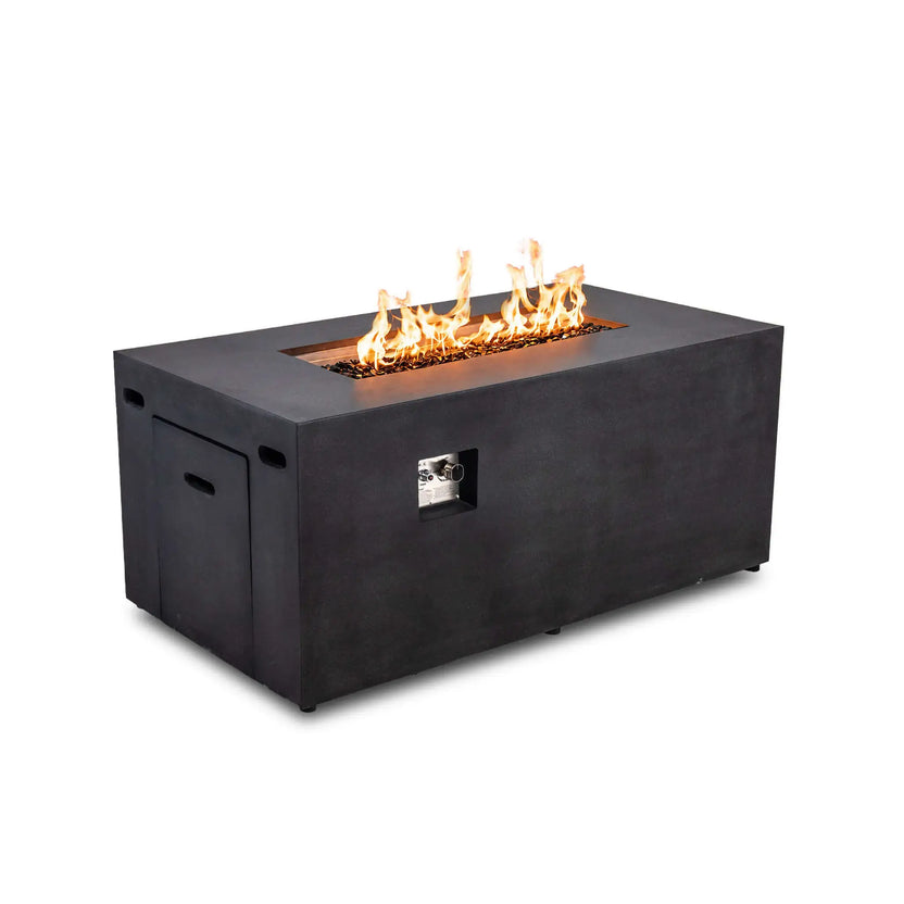 Angled view of the black Flame Havens Refuge Series 56 x 30 x 24-inch rectangular GFRC concrete propane gas fire pit burning over tempered black fire glass. The recessed ignition controls, hidden propane tank drawer, ventilation openings, and clean modern profile are visible.